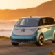 2026 Volkswagen ID.Buzz electric minivan parked on coastal cliff road at golden hour sunset