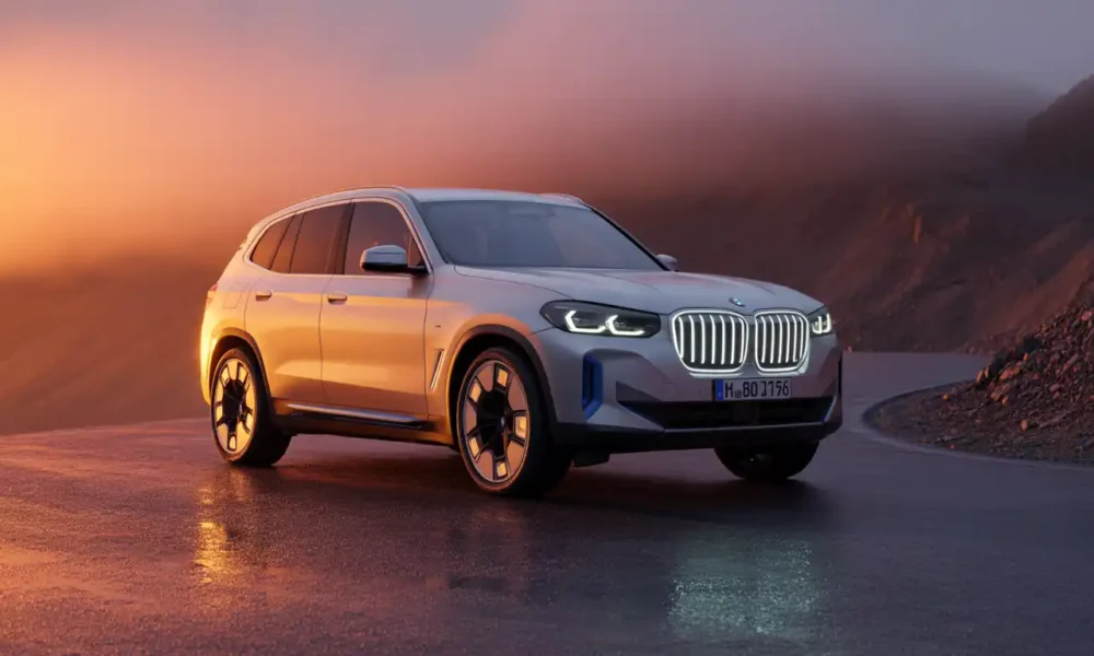 2027 BMW iX3 electric SUV parked on a dramatic mountain road at sunset