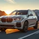 2026 BMW X5 luxury SUV front view in alpine white on mountain road
