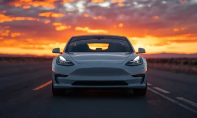 2026 Tesla Model 3 electric sedan front three-quarter view on open highway at sunset