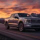 Ford F-150 Lightning Platinum electric truck parked on a scenic mountain road at sunset