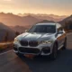 2026 BMW iX3 Neue Klasse electric SUV driving on mountain highway at golden hour showing full exterior design and range capability