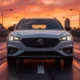 2026 MG ZS Hybrid+ in Pearl White on urban boulevard at golden hour with city skyline in background
