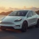 2026 Tesla Model Y in Pearl White on a coastal road at golden hour, featured in this Tesla Y reviews guide.