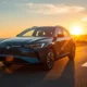 2026 BYD Dolphin electric hatchback showing its range potential on a coastal highway at sunset